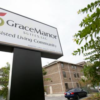Entrance sign for Grace Manor Assisted Living Community with the building in the background.