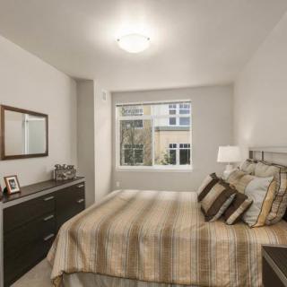 A neatly decorated bedroom with a bed, dresser, and window view.