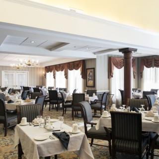 An elegant restaurant dining room featuring neatly arranged tables and chairs with formal place settings.