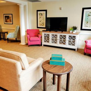 A cozy living room with colorful armchairs, a beige sofa, and a flat-screen TV.