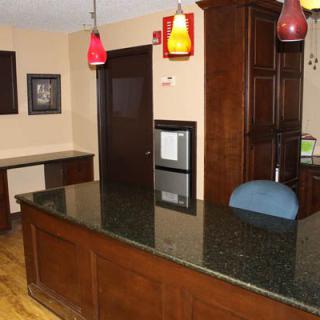 A reception desk with wooden finishes and colorful pendant lights in an office setting.