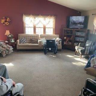 A cozy living room with sofas, a television, and wheelchairs.