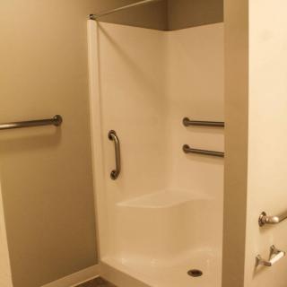 A modern, accessible shower with grab bars in a clean bathroom.