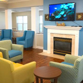 A cozy living room featuring colorful seating arrangements and a fireplace, equipped with a television for entertainment.