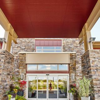 A modern building entrance with a stone facade and decorative plants.