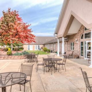 A patio area with tables and chairs outside a building, featuring a vibrant autumn tree.