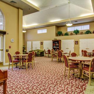 A spacious and well-lit dining area with multiple tables and chairs, featuring a patterned carpet.