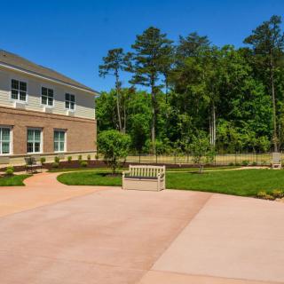 A modern building with a landscaped garden and pathway under a clear blue sky.