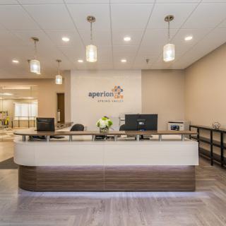 A modern office reception area with a front desk and computers.