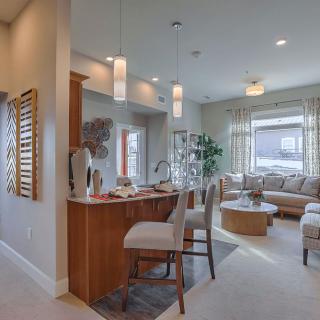 A modern open-concept living room and kitchen area featuring neutral decor and contemporary furnishings.