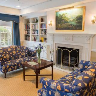 A cozy living room with a fireplace, bookcase, and colorful sofas.
