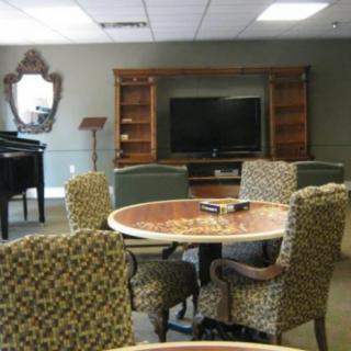 A cozy living room setup with patterned chairs around a table, a television, and a piano.