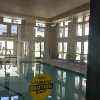 A serene indoor pool area illuminated by natural light, showcasing a caution sign for safety.