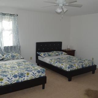 A simple bedroom with two twin beds and a window, featuring minimalist decor.