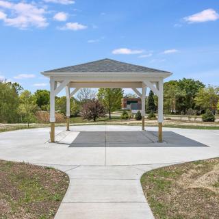 A gazebo in a park setting under a clear blue sky.