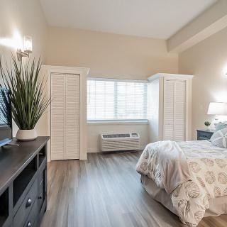 A modern bedroom with light walls, hardwood floors, and stylish furnishings.