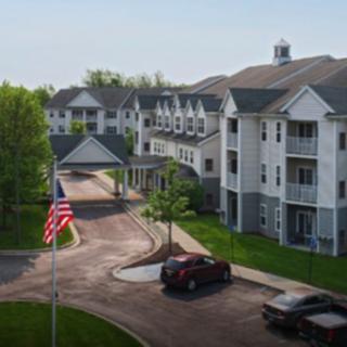 A residential apartment complex with a driveway and parked cars.