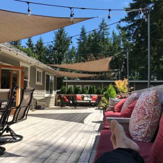 A cozy outdoor patio with sunshade sails and string lights, perfect for relaxation.