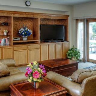 A cozy living room with a large sofa, a television on the bookshelf, and colorful flowers on the coffee table.