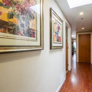 A hallway with framed artwork and wooden flooring.