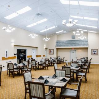 A spacious dining room with neatly arranged tables and chairs under bright ceiling lights.