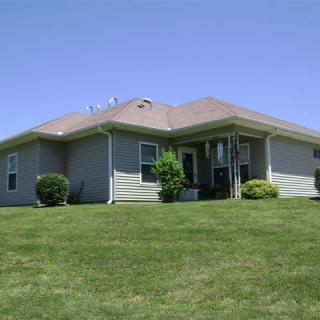 A suburban house with a well-maintained lawn under a clear blue sky.