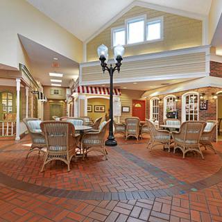 A cozy indoor dining area with wicker furniture and a brick floor, featuring decorative street lamp-style lighting.