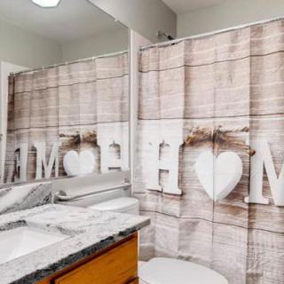 A bathroom with a wooden-themed shower curtain and a well-organized countertop.