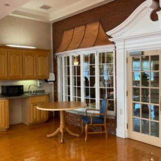 A cozy kitchen and dining area with wooden cabinets, a round table, and large windows.