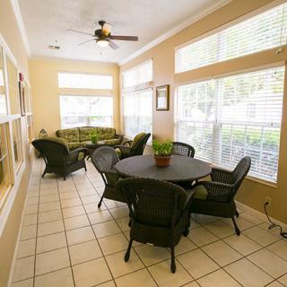 A cozy sunroom with rattan furniture and large windows.