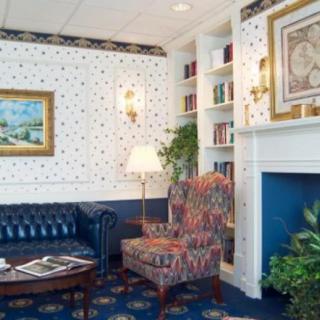 A traditionally decorated living room with a patterned armchair, bookshelf, and fireplace.