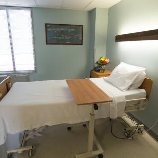 A clean and organized hospital room with a single bed and bedside table.
