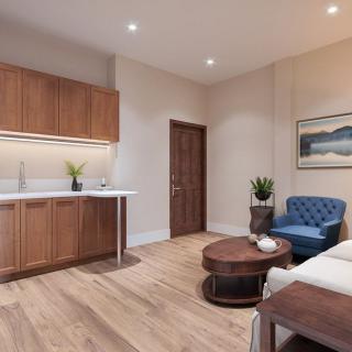 A modern and cozy living space featuring a small kitchen area, wooden flooring, and comfortable seating.