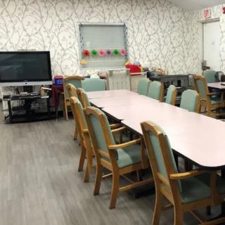 A conference room with a large table, surrounded by chairs and equipped with a television.