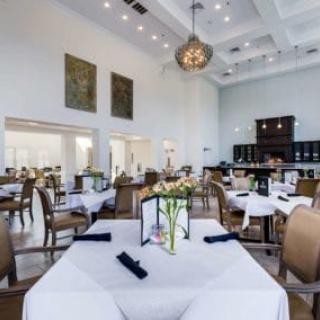 An elegant restaurant interior featuring neatly arranged tables and chairs, with a decorative chandelier hanging from the ceiling.