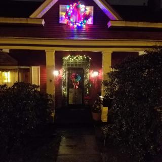 A festive house adorned with colorful Christmas lights and decorations at night.