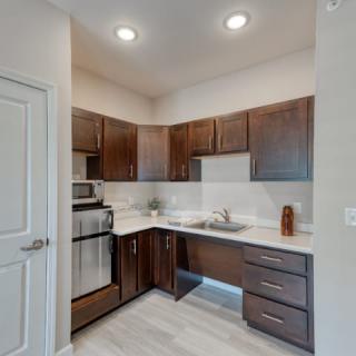 A modern apartment kitchen with dark wood cabinets and stainless steel appliances.