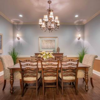 Elegant dining room with a central wooden table and chandelier lighting.