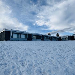 A row of modern buildings surrounded by snow under a cloudy sky.