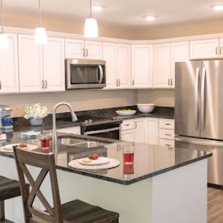 A modern kitchen featuring white cabinets, stainless steel appliances, and a stylish island with seating.