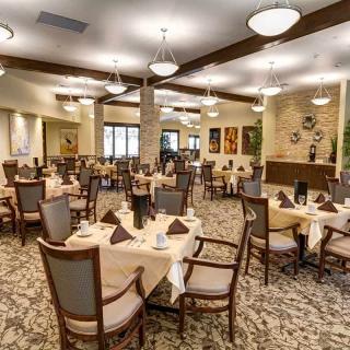 A well-lit dining room with neatly arranged tables and chairs.