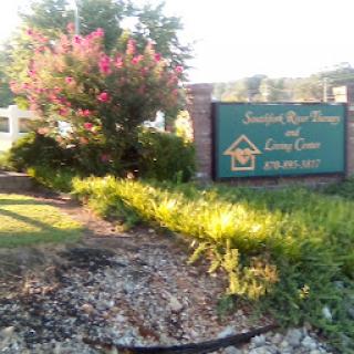 Welcome sign for a community center surrounded by vibrant flowers and greenery.