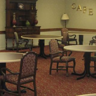An empty dining area with several round tables and upholstered chairs.