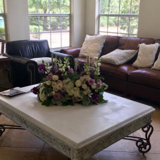 A cozy living room featuring a stylish coffee table adorned with a beautiful flower arrangement and comfortable sofas.