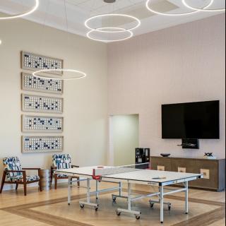A modern conference room featuring a central table, seating, contemporary artwork, and a mounted television.