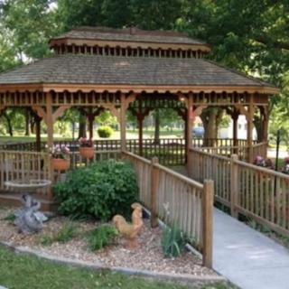 A beautiful wooden gazebo in a lush garden setting with a paved pathway.
