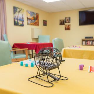 A cozy activity room set up for a game of bingo, featuring tables and chairs in a warm environment.