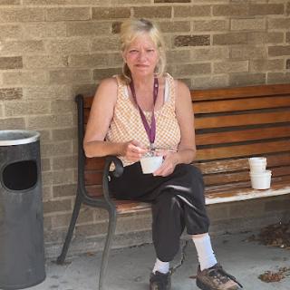 A person enjoying a snack while seated on a bench in an outdoor area.