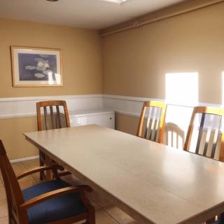 A simple conference room with a long table and several wooden chairs.