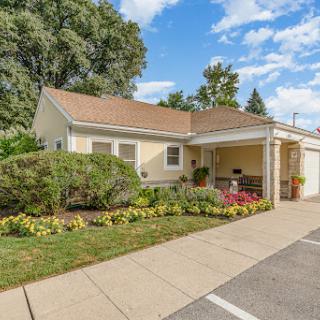 A charming residential home with a well-maintained garden and clear blue skies.